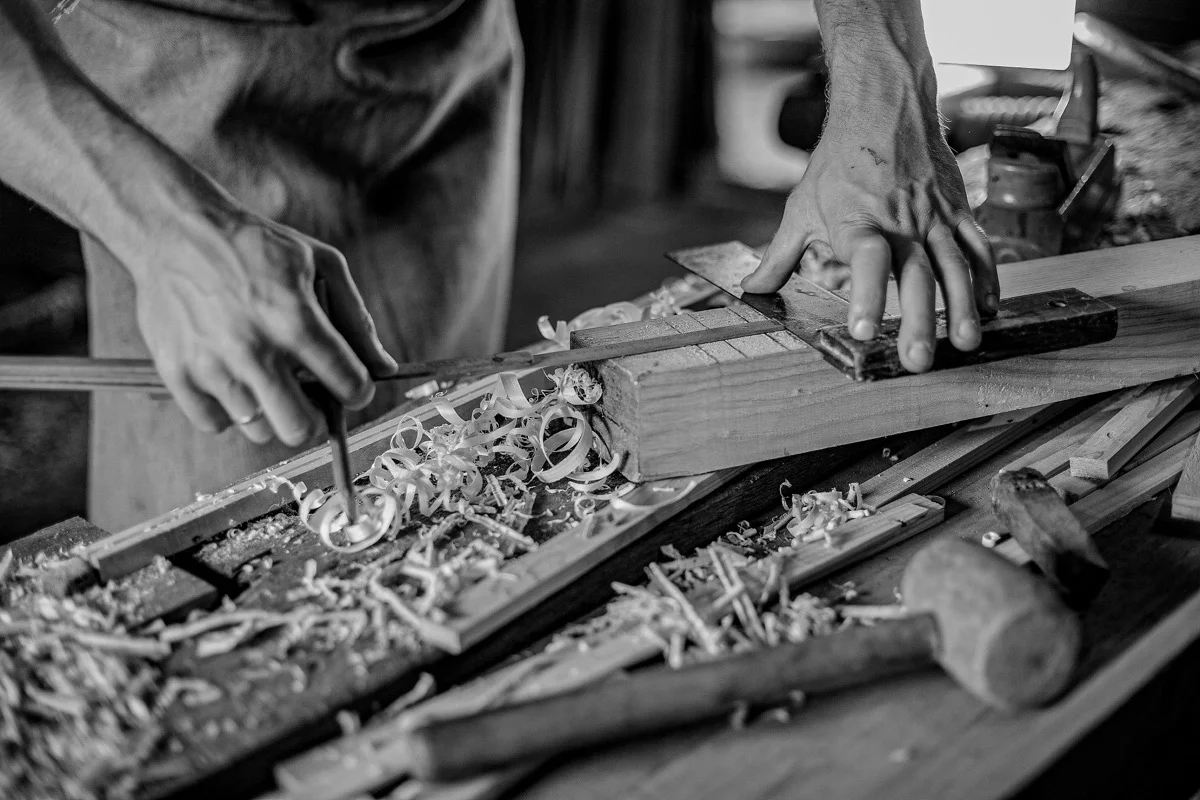 Craftsman hand planing timber, wood shavings curling