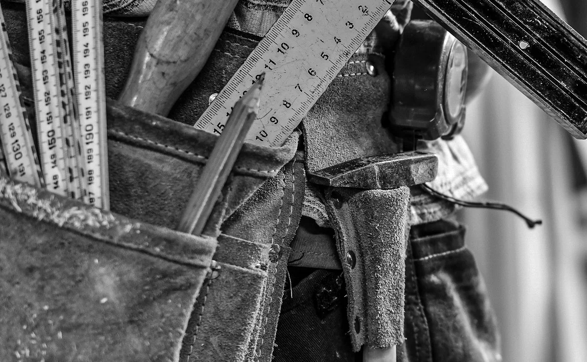 Carpenter with square and measuring tools in tool belt